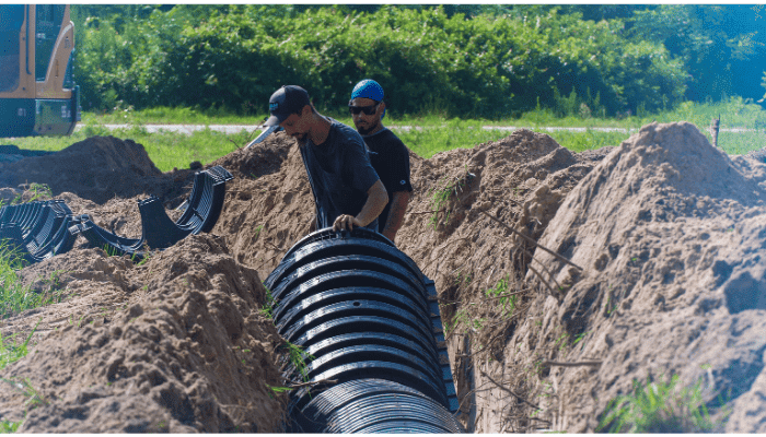 Technicians installing a new septic system drainfield in an excavated trench