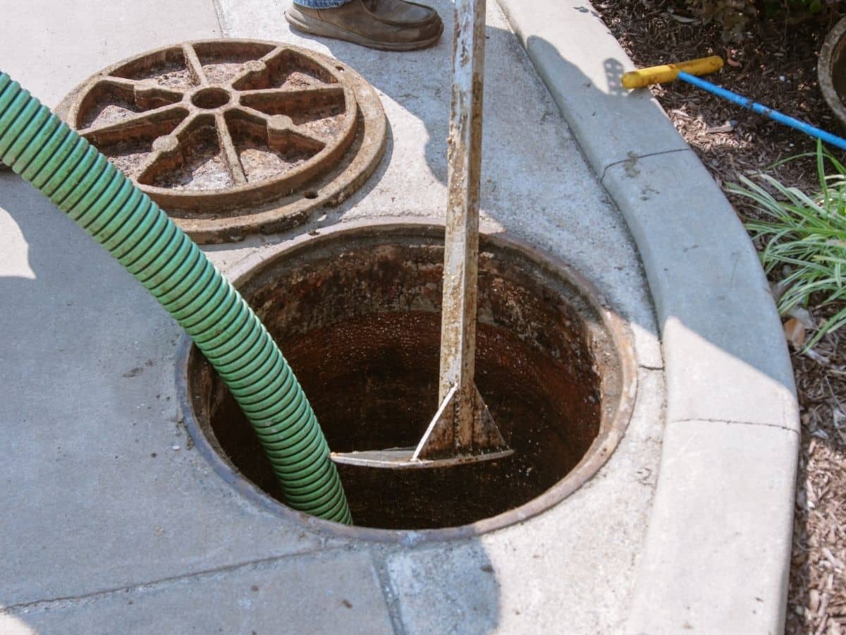 Technician performing septic tank service with hose and cleaning tools at a Mt. Olive, NC property.